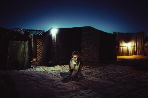 a man sitting on the ground in front of a tent at Hôtel Camping La Liberté in Merzouga