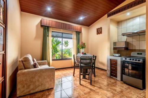 a living room with a table and a kitchen at Aunty Arenal Lodge in Fortuna
