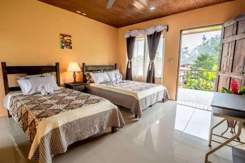 a bedroom with two beds and a large window at Aunty Arenal Lodge in Fortuna