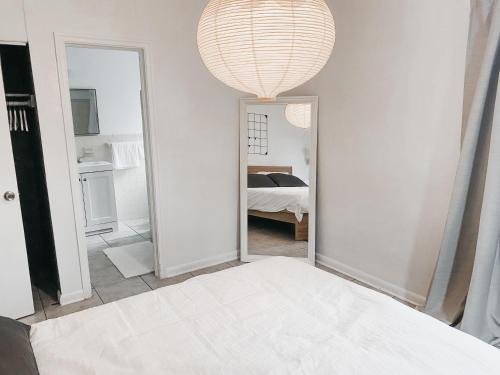 a white bedroom with a mirror and a bed at Lovely Bohemian Apartment in Fort Lauderdale