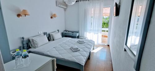 a white bedroom with a bed and a window at Hotel Rania in Loutra Edipsou