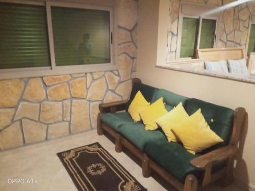 a living room with a green couch with yellow pillows at Le Gite du Barrage in Zaouia Ben Smine