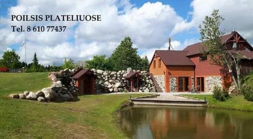 a house with a pond in front of a house at Poilsio namelis Plateliai in Plateliai