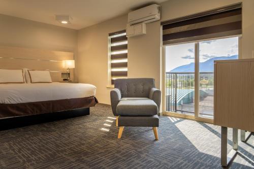 a hotel room with a bed and a chair and a window at Quality Inn Sunshine Suites in Terrace