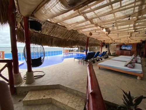 a beach area with a pool, chairs, tables and umbrellas at Hotel Isla Real in Tierra Bomba