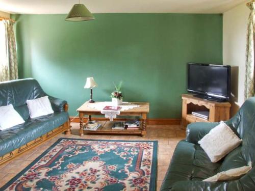 uma sala de estar com um sofá e uma televisão em Horse Shoe Cottage em Bradley in the Moors