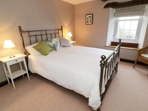 a bedroom with a large white bed and a window at Hope Cottage in Leyburn