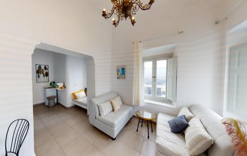 a living room with a white couch and a chandelier at NEOKLASSIKO KOUKOULI in Fira