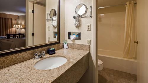 a bathroom with a sink and a toilet and a mirror at Best Western Center Pointe Inn in Branson