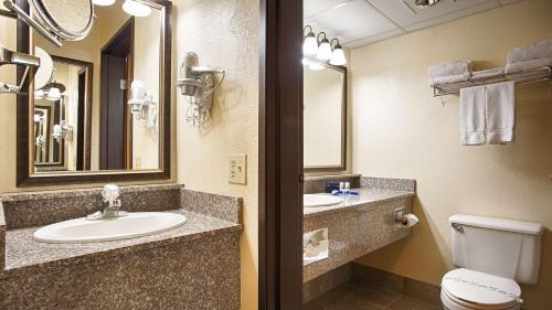 een badkamer met 2 wastafels, een toilet en een spiegel bij Best Western Music Capital Inn in Branson