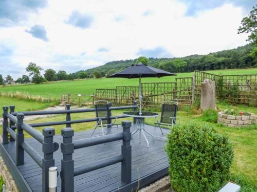 a wooden deck with a table and an umbrella at Poacher's Rest in Great Rowsley