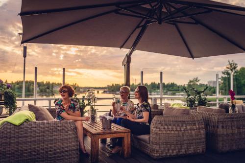 three people sitting on a patio under an umbrella at Radisson Blu Hotel, Oulu in Oulu