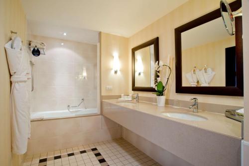 uma casa de banho com um lavatório, uma banheira e um espelho. em Radisson Blu Hotel, Paris Boulogne em Boulogne-Billancourt