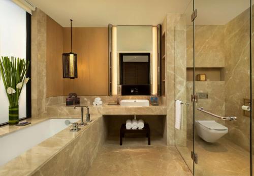 uma casa de banho com uma banheira, um lavatório e um WC. em Radisson Blu Bali Uluwatu em Uluwatu