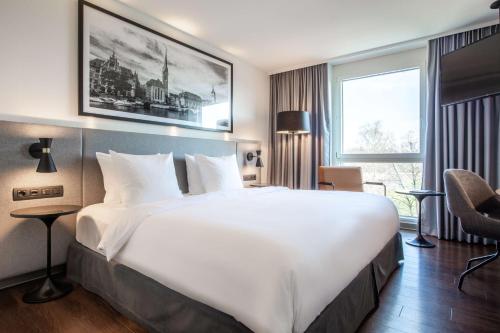 a hotel room with a large white bed and a window at Radisson Hotel Zurich Airport in Rümlang