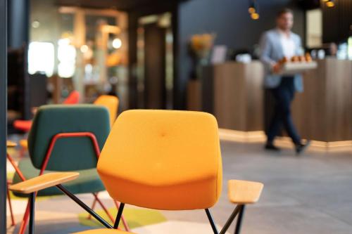a row of chairs in a restaurant with a man in the background at Radisson Hotel Zurich Airport in Rümlang