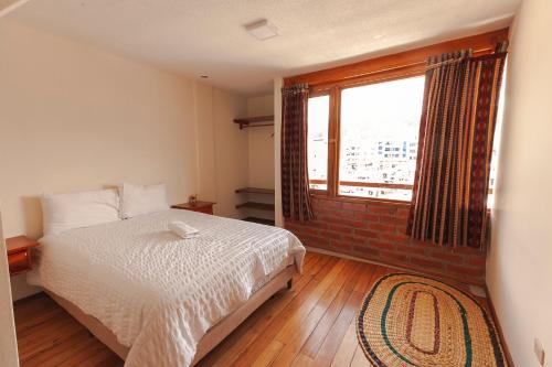 a bedroom with a bed and a large window at Los Ponchos Inn Apartasuite in Otavalo