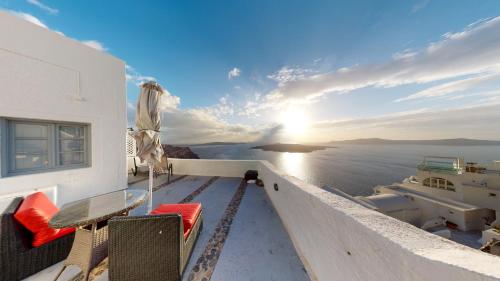 a balcony with a table and chairs and the sunset at NONI STUDIOS in Fira