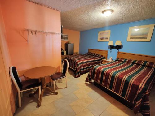 a hotel room with two beds and a table at Western Motel in Deming
