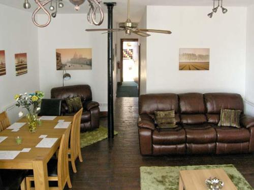 a living room with a leather couch and a table at The Reiver's Retreat in Haltwhistle