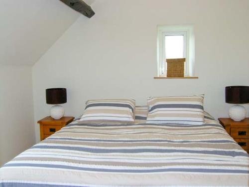 a bedroom with a bed with two pillows and a window at Harrison's Cottage in Llandegla