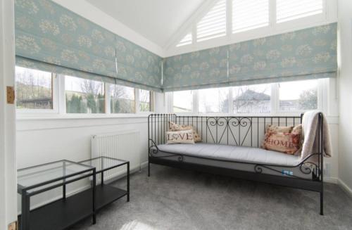 una habitación con un banco en una ventana con una mesa en Kilburn Holiday Cottage, en Largs