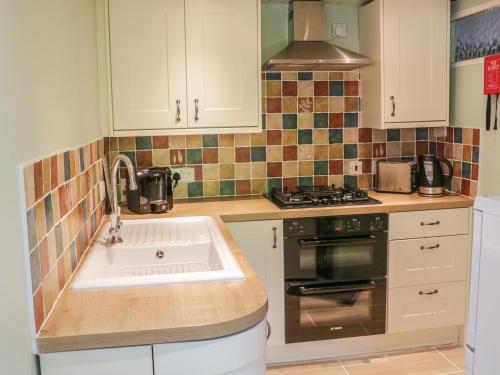 a kitchen with a sink and a stove at 8 Stonegate in High Bentham