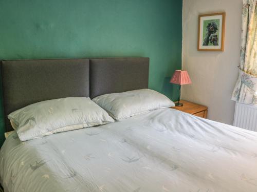 a bed with two pillows and a green wall at 8 Stonegate in High Bentham
