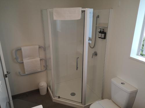 a bathroom with a shower with a toilet and towels at Airport Palms Motel in Christchurch
