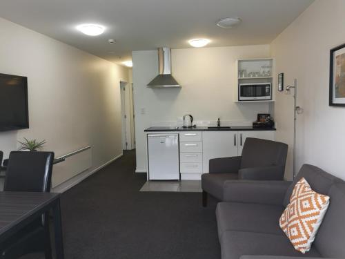 a living room with a couch and a kitchen at Airport Palms Motel in Christchurch
