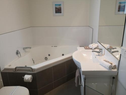 a bathroom with a tub and a sink and a toilet at Airport Palms Motel in Christchurch