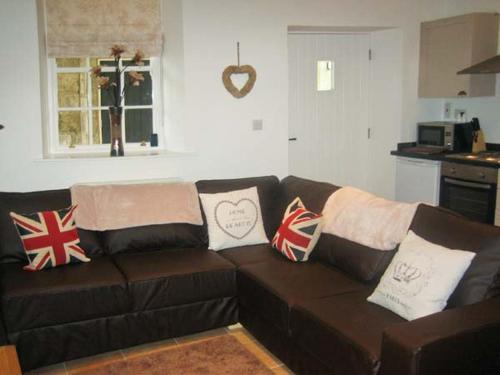 um sofá castanho numa sala de estar com almofadas em No 5 The Stables em Pateley Bridge