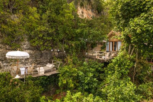 a building with chairs and an umbrella on a mountain at The Korowai in Uluwatu