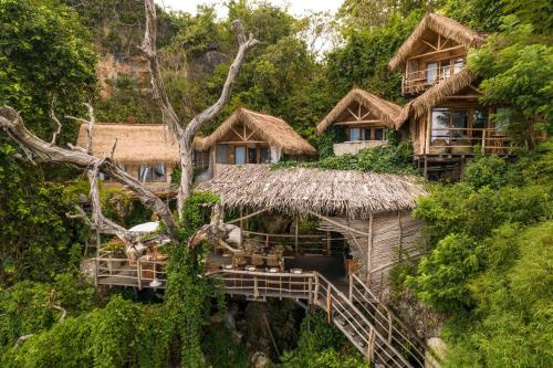 un grupo de cabañas en una colina con árboles en The Korowai en Uluwatu