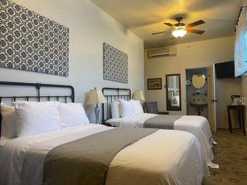 a hotel room with two beds and a ceiling fan at Hotel Sutter in Sutter Creek
