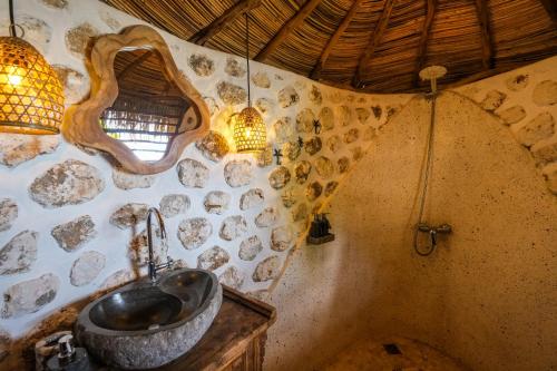 baño con lavabo en una pared de piedra en The Korowai en Uluwatu