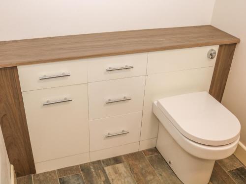 een badkamer met een toilet en witte kasten bij Providence Apartment in Epworth