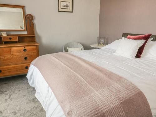 a bedroom with a large white bed with a dresser at The Snug in Keighley