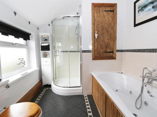 a bathroom with a tub and a glass shower at Sands End Cottage in Redcar