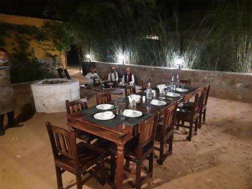 a long table with people sitting around it at night at Ranthambhore Bagh Dwar Camp in Khilchipur