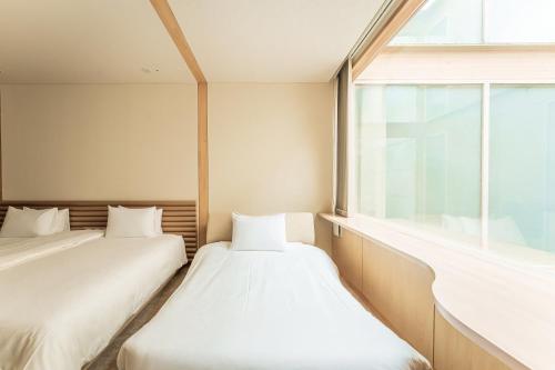 two beds in a room with a window at Shonai Hotel Suiden Terrasse in Tsuruoka