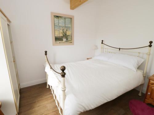 ThorntonにあるThe Hen Houseの白いベッドと壁の絵が備わるベッドルーム1室が備わります。