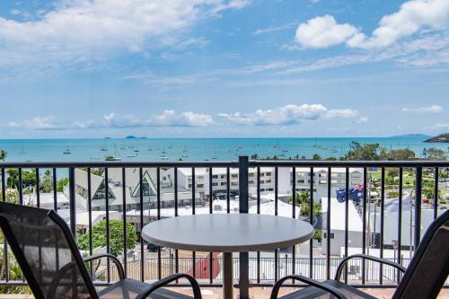 a balcony with a table and chairs and a view of the ocean at Ocean View Apartment 14 in Airlie Beach