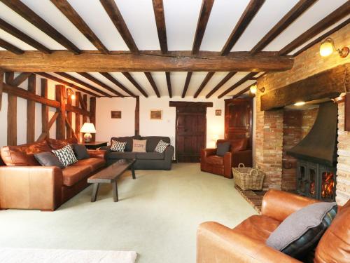a living room with leather furniture and a fireplace at Harbourne Oast in Tenterden
