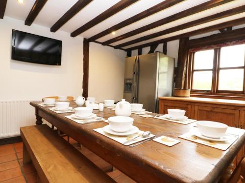 a large wooden table with bowls and plates on it at Harbourne Oast in Tenterden