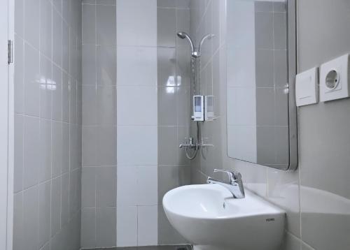 Baño blanco con lavabo y espejo en Cordex Hotel Ancol, en Yakarta