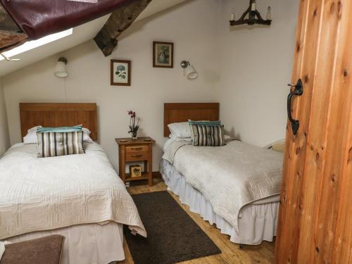 a bedroom with two beds and a wooden floor at Snape Castle, The Undercroft in Bedale