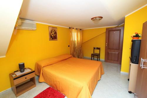 1 dormitorio con paredes amarillas, 1 cama y TV en Bed and Breakfast Vibo Mare en Vibo Valentia Marina