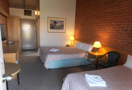 een hotelkamer met 2 bedden en een bakstenen muur bij All Rivers Accommodation in Echuca