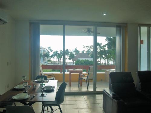 a living room with a table and chairs and a balcony at Beachfront Apartment Your Home in Cozumel in Cozumel